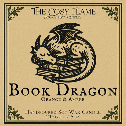 Book Dragon candle label design by The Cosy Flame, featuring an illustration of a small dragon curled up on a stack of books, featuring the scents orange and amber.