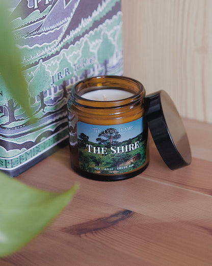 Amber glass candle jar labelled ‘The Shire’ from The Cosy Flame, scented with tea and rose, and The Hobbit book in the background.